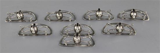 A set of eight Edwardian novelty silver menu holders modelled as fox masks on crossed riding crops, 2.75in.